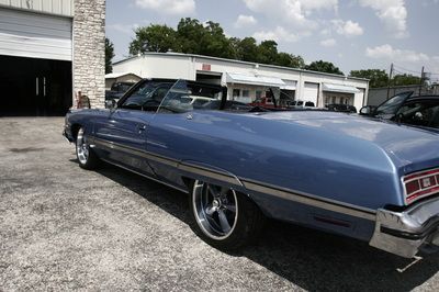 A blue convertible is parked in front of a garage
