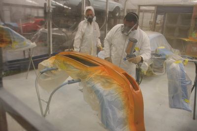 Two men are painting a car