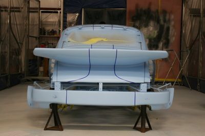 A blue car is sitting on a wooden stand in a garage