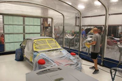 A man is standing next to a car in a garage