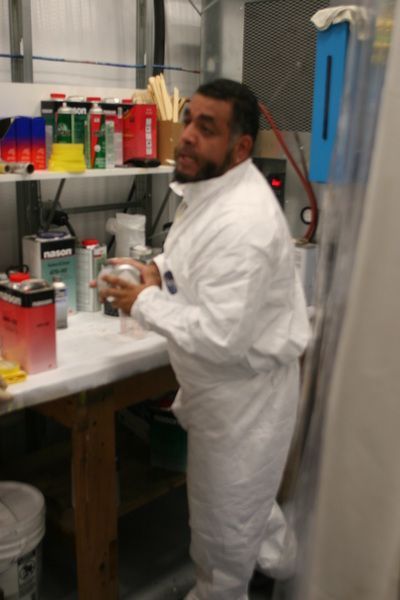 A man in a white suit is standing in front of a table