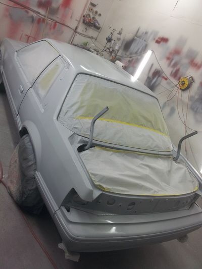 A white car is being painted in a garage
