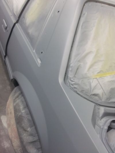 A white car is being painted in a garage