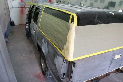 A gray van is being painted in a garage