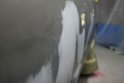 A person is sanding a car door in a garage