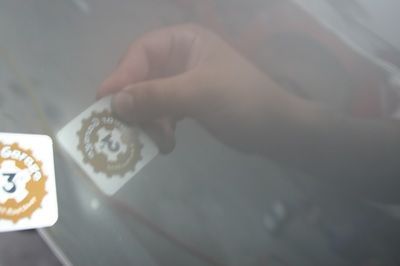 A person is putting a sticker on the windshield of a car