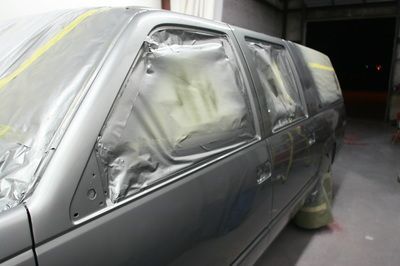 A gray suv is being painted in a garage