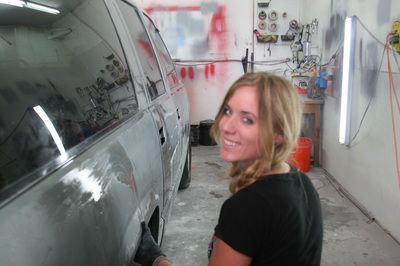 A woman is standing next to a car in a garage