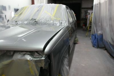 A silver car is being painted in a garage