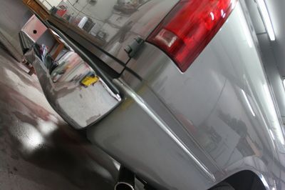 A silver truck with a red tail light is parked in a garage
