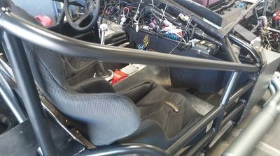 The inside of a race car with a black seat and steering wheel