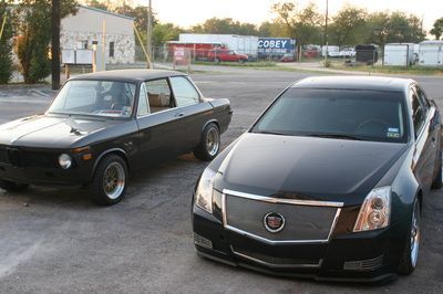 A bmw and a cadillac are parked next to each other in a parking lot