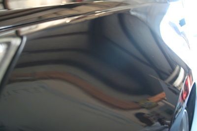 A close up of a black car 's hood in a garage