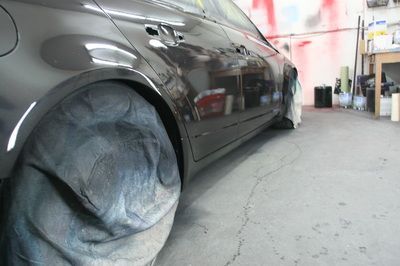 A black car is being painted in a garage