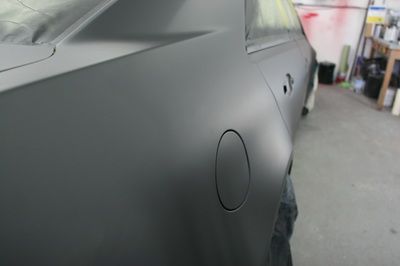 A black car is being painted in a garage