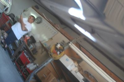 A man in a white shirt is standing in a garage