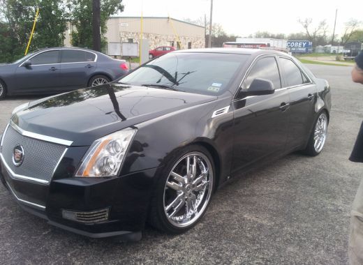A black cadillac is parked in a parking lot