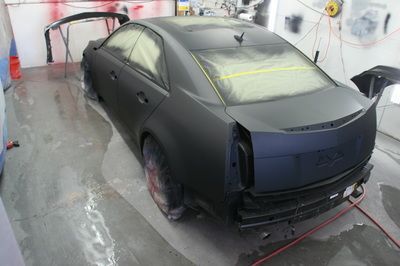 A black car is being painted in a garage