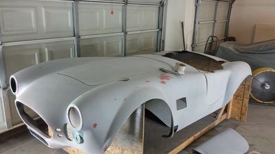 A car body is sitting on a wooden table in a garage