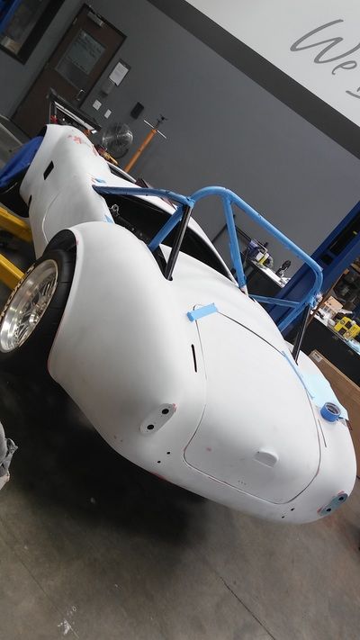 A white race car is sitting on a lift in a garage
