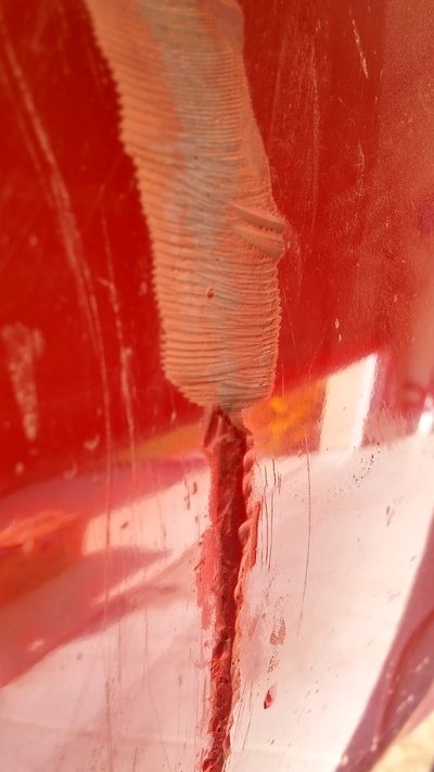 A close up of a red car with a hole in it