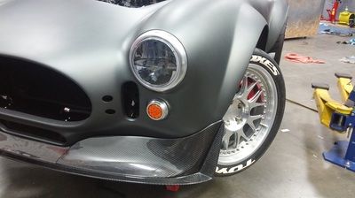 A black car is parked in a garage next to a lift