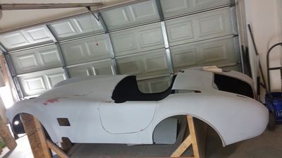 A white sports car is sitting in a garage next to a garage door