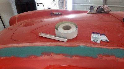 A roll of tape is sitting on top of a red car