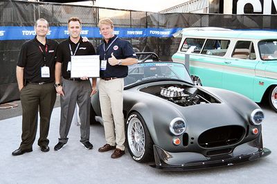 A group of men standing in front of a car holding a certificate