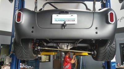 A man is working on the underside of a car on a lift