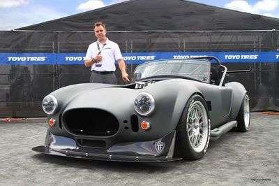 A man is standing in front of a toyo tires car