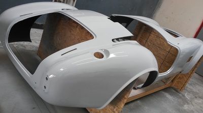 A white car body is sitting on a wooden crate