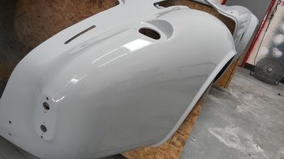 A white motorcycle fender is sitting on top of a wooden table