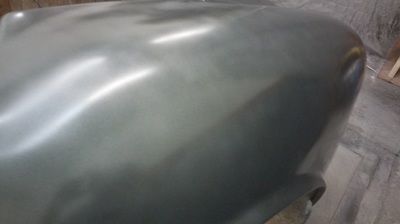 A close up of a car hood on a wooden floor