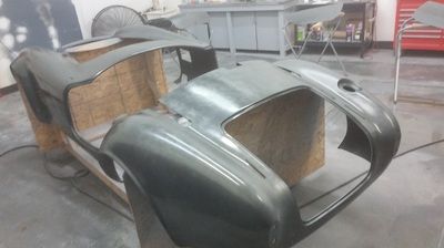 A car body is sitting on top of a wooden box in a garage