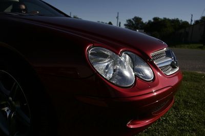 A red car is parked in the grass on the side of the road