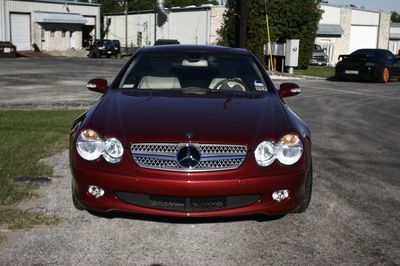 A red mercedes is parked in a parking lot
