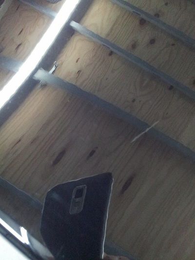 A person is standing in front of a wooden ceiling