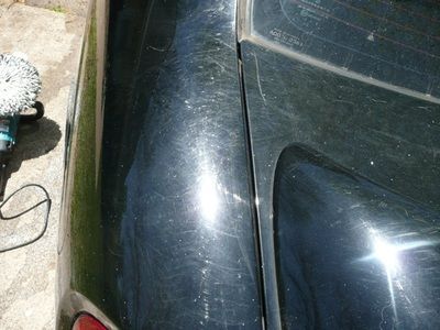 A black car is being polished with a polisher