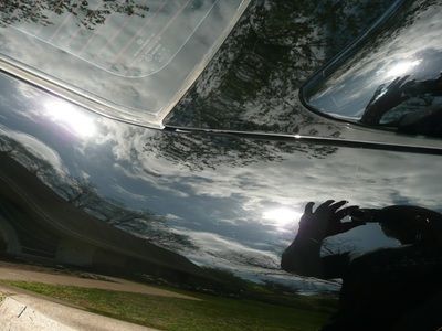 A person is taking a picture of a car with a cell phone