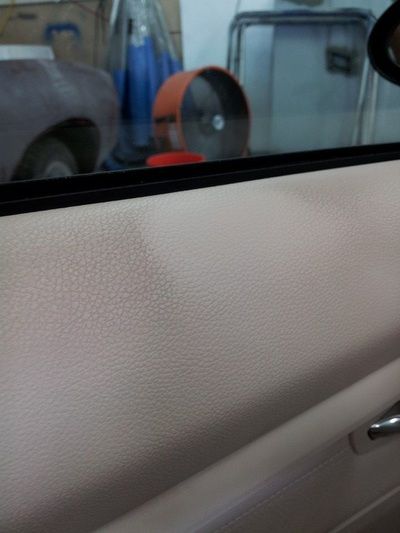 A close up of a car door with a fan in the background