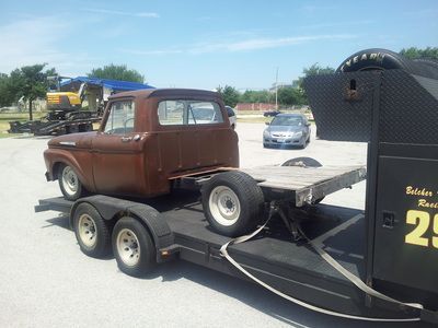 A brown truck is on a trailer with the number 20 on it