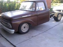 A brown pickup truck is parked in a driveway next to a trailer