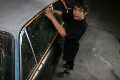 A boy in a black shirt is working on a car