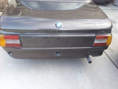 A bmw is parked in a driveway with the trunk open