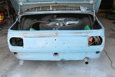 A blue car with the trunk open and a tire in it