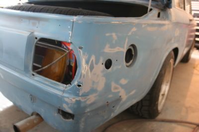 A blue car with the trunk open is sitting in a garage