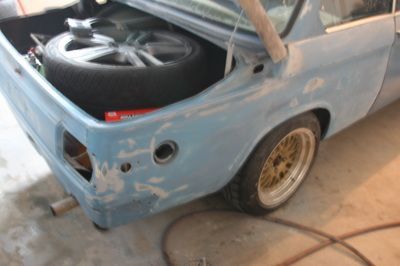 A blue car with a spare tire in the trunk