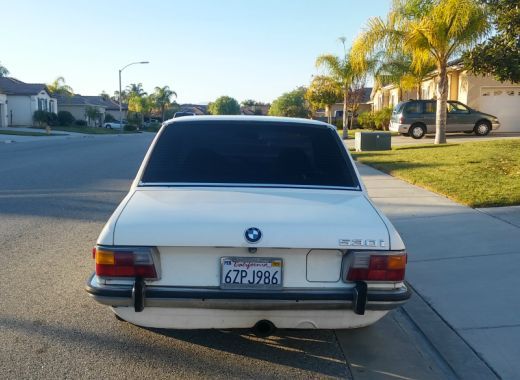 A white bmw is parked on the side of the road