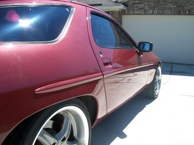 A red car is parked in front of a garage